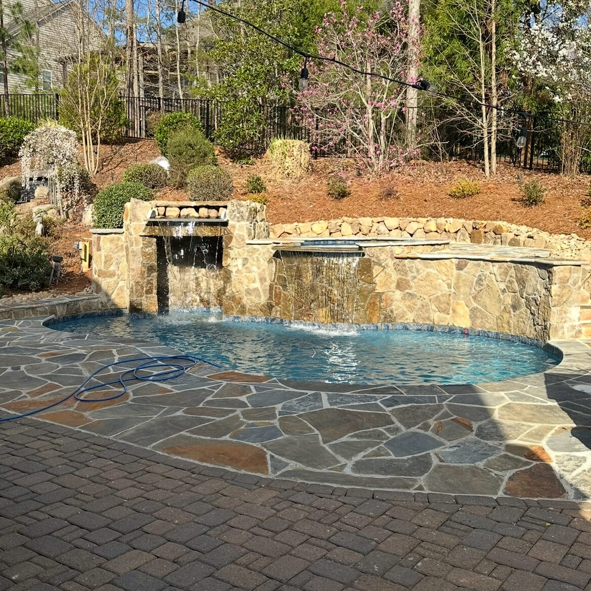 Completed custom plunge pool with flagstone patio spa and grotto - daytime view Charlotte NC